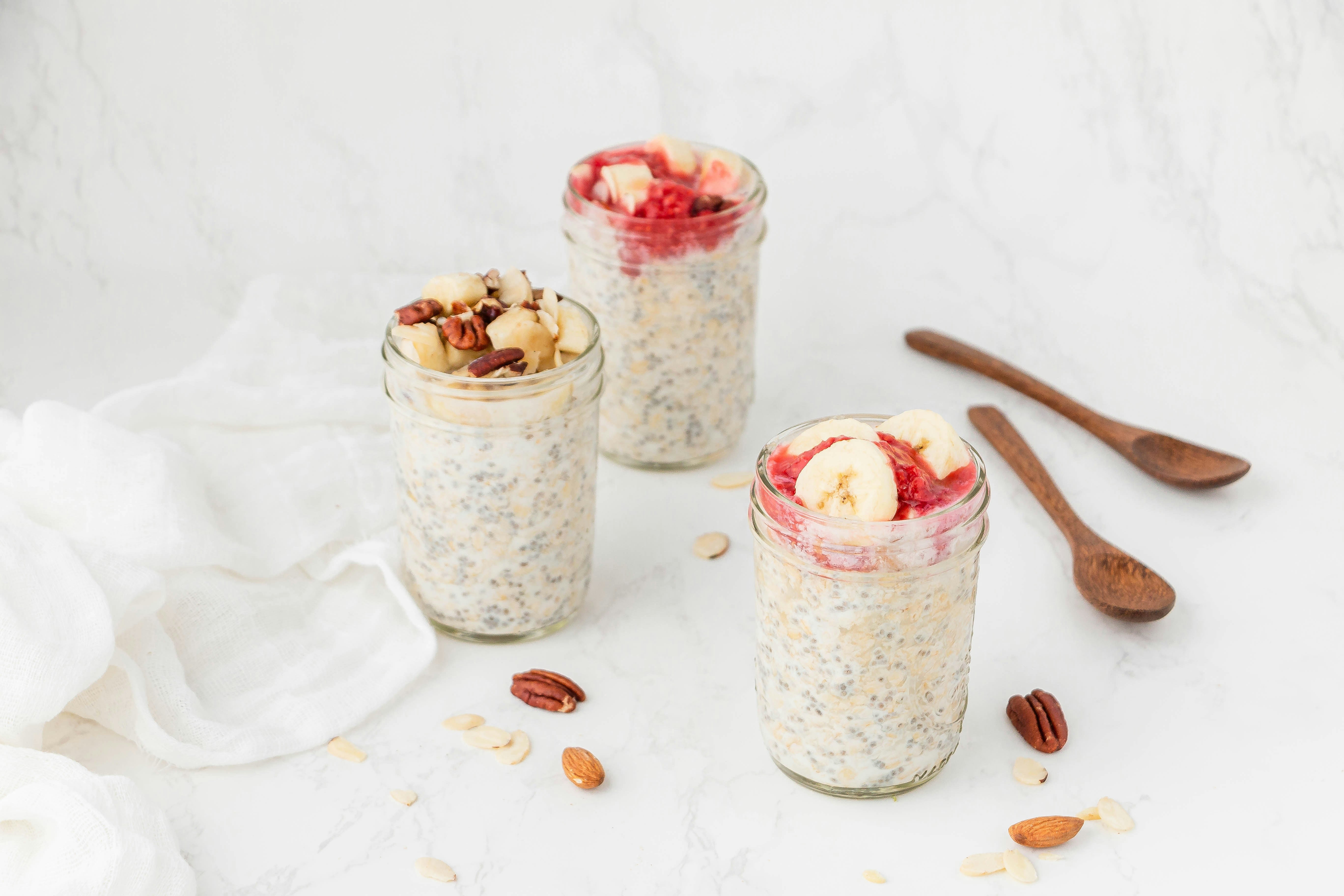 Three jars filled with oatmeal, nuts, and fruit, showcasing nutritious gluten-free breakfast options for those with gluten intolerance.