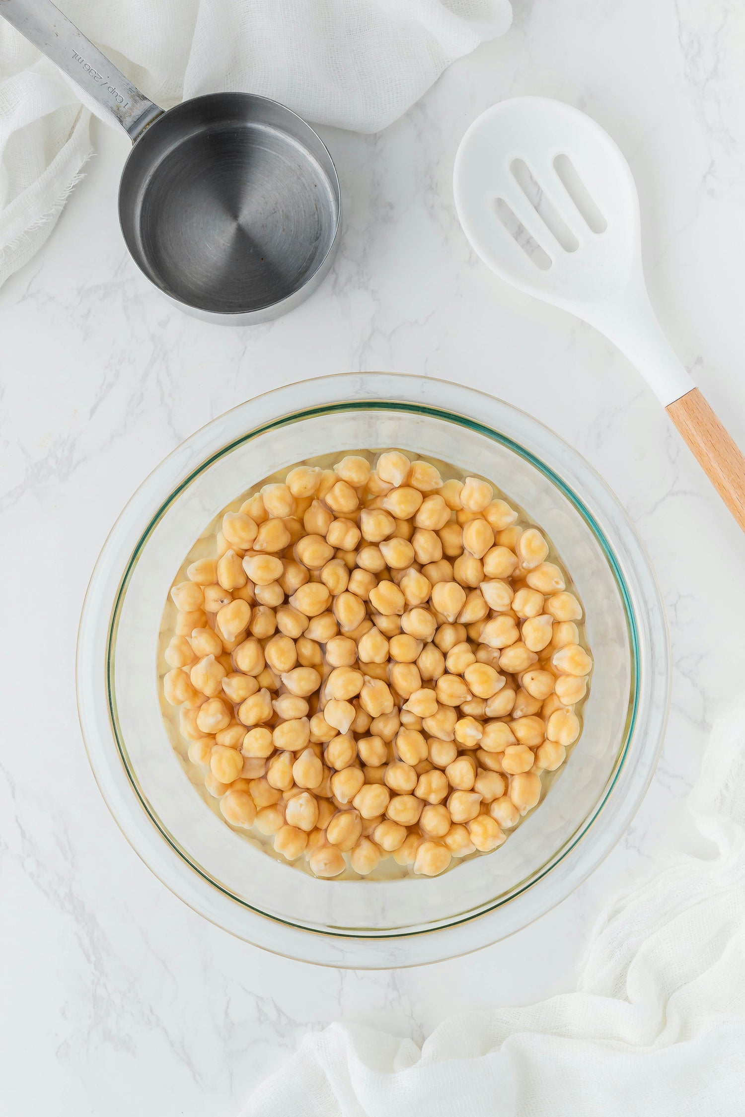 A bowl of chickpeas on a white table, highlighting the potential use of chickpea water (aquafaba) as an egg substitute in recipes for those managing egg intolerance.