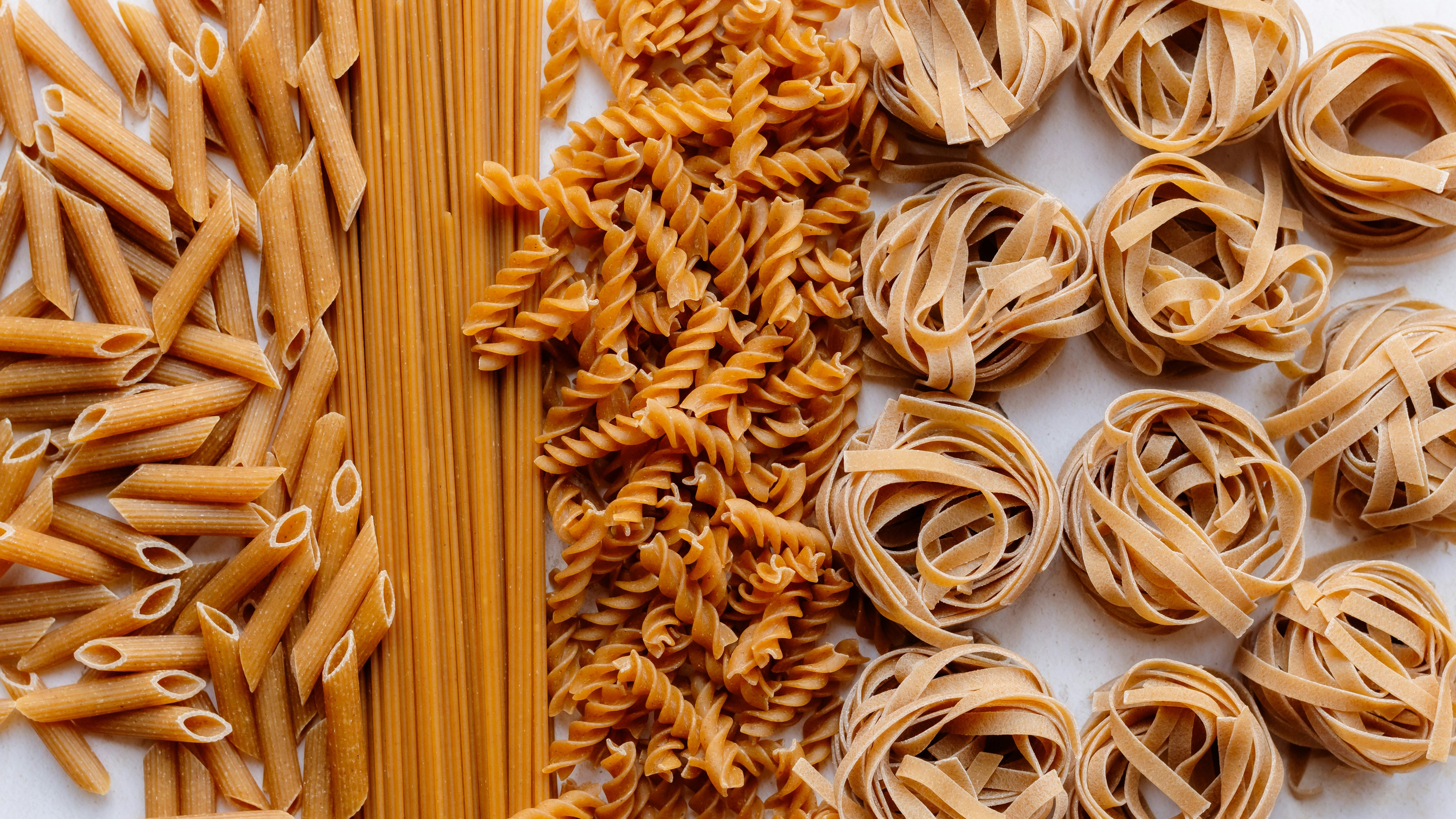 A table filled with various types of pasta, a staple food that can trigger symptoms for individuals with gluten sensitivity.