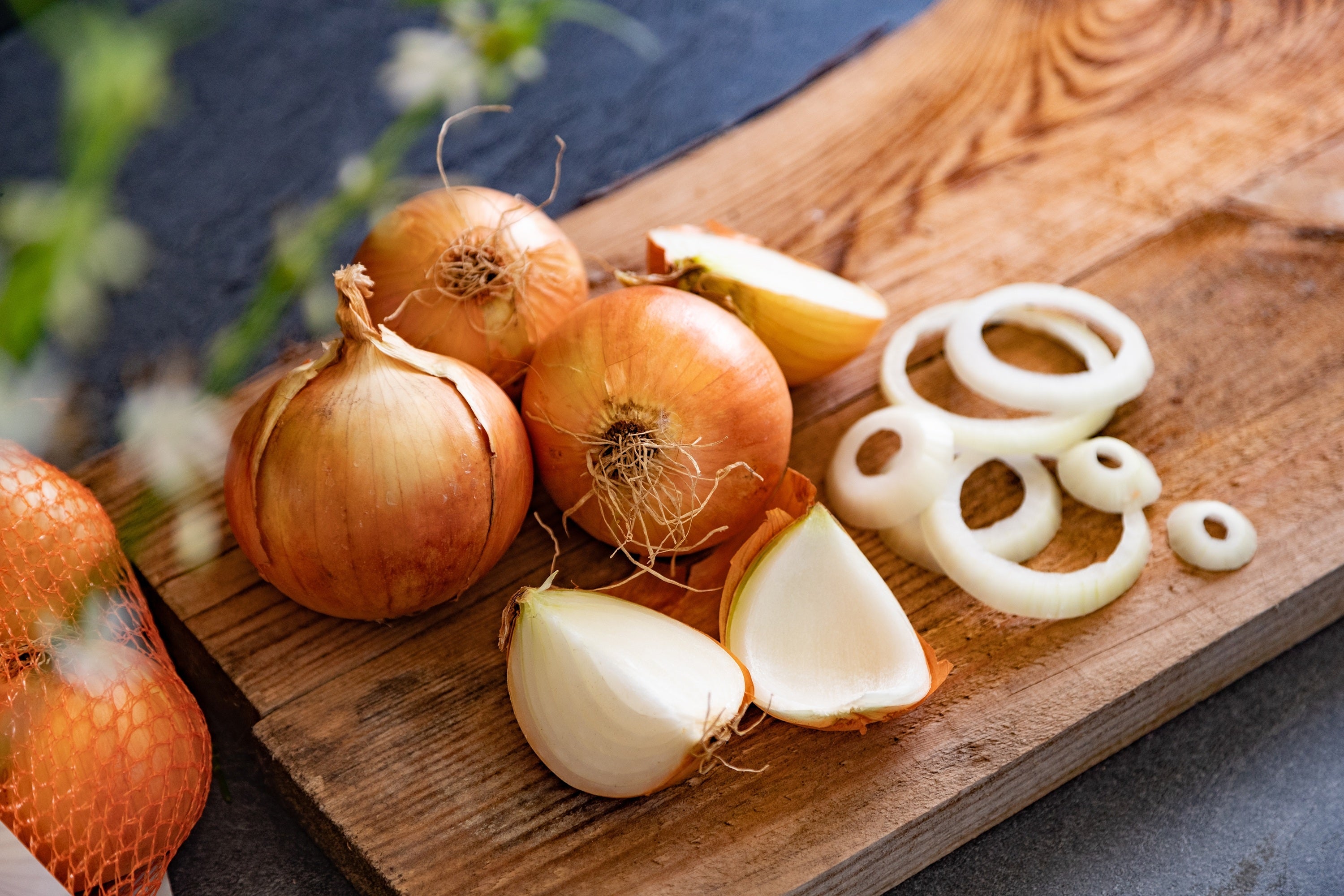 Chopped and whole onions arranged on a wooden cutting board, ready for cooking preparation.