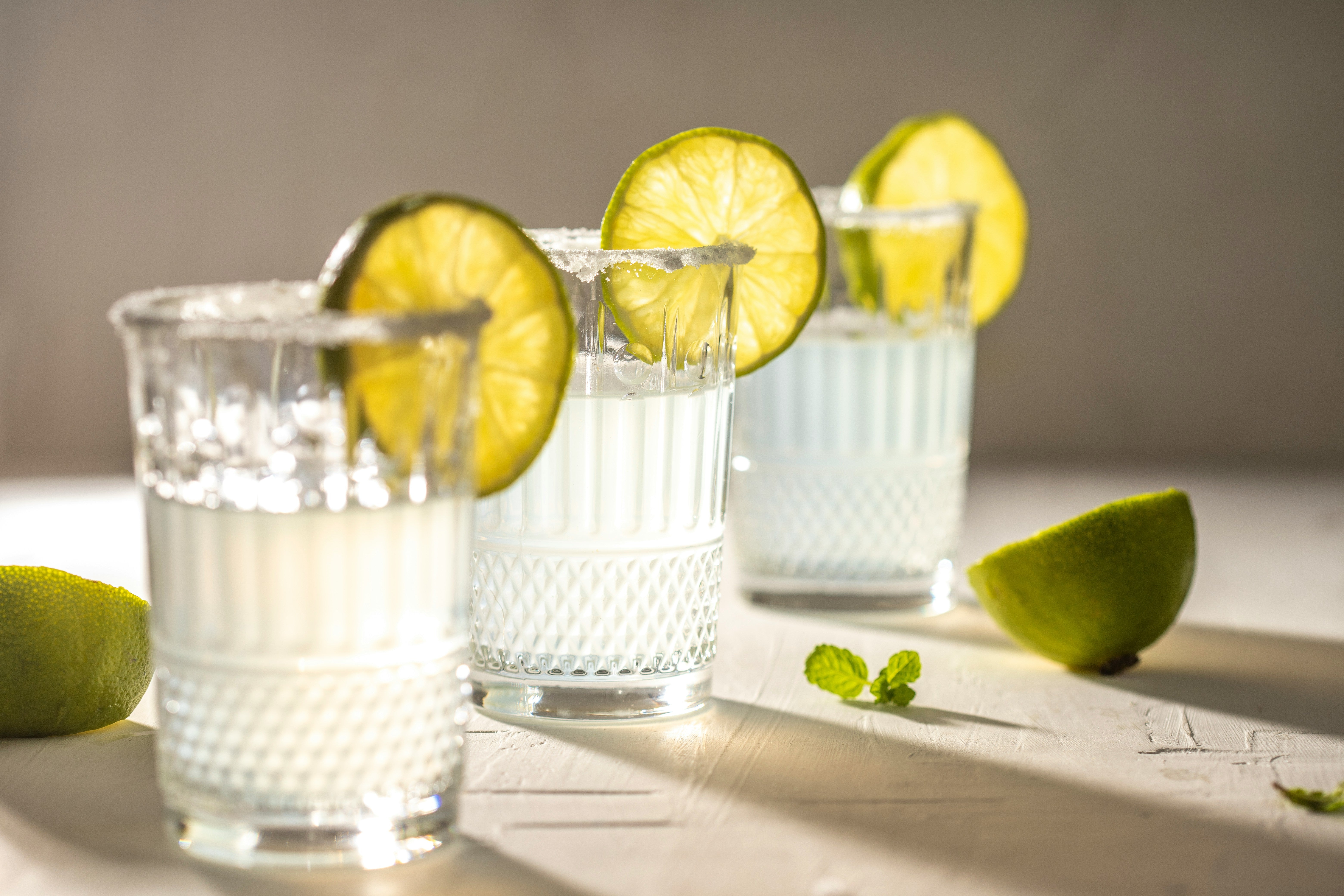 Three glasses of water with lime wedges, a simple and hydrating alternative for individuals managing alcohol intolerance at social gatherings.