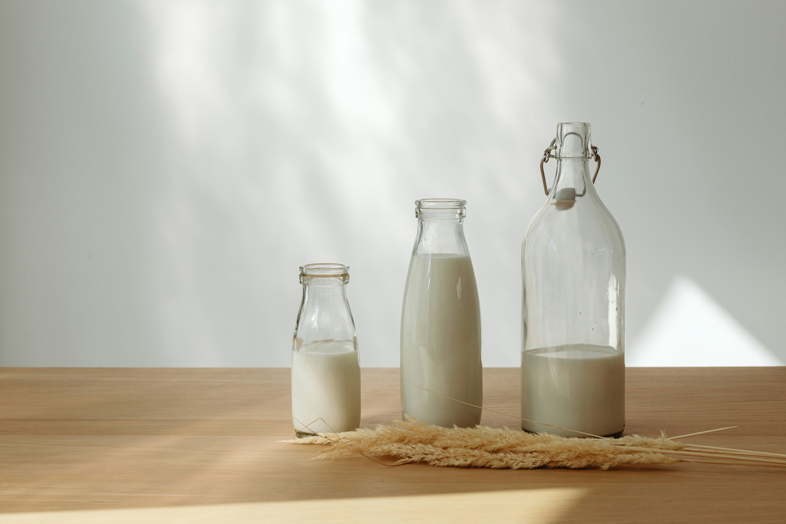 Two bottles of milk on a wooden table, representing a common source of lactose that can trigger intolerance symptoms in sensitive individuals.