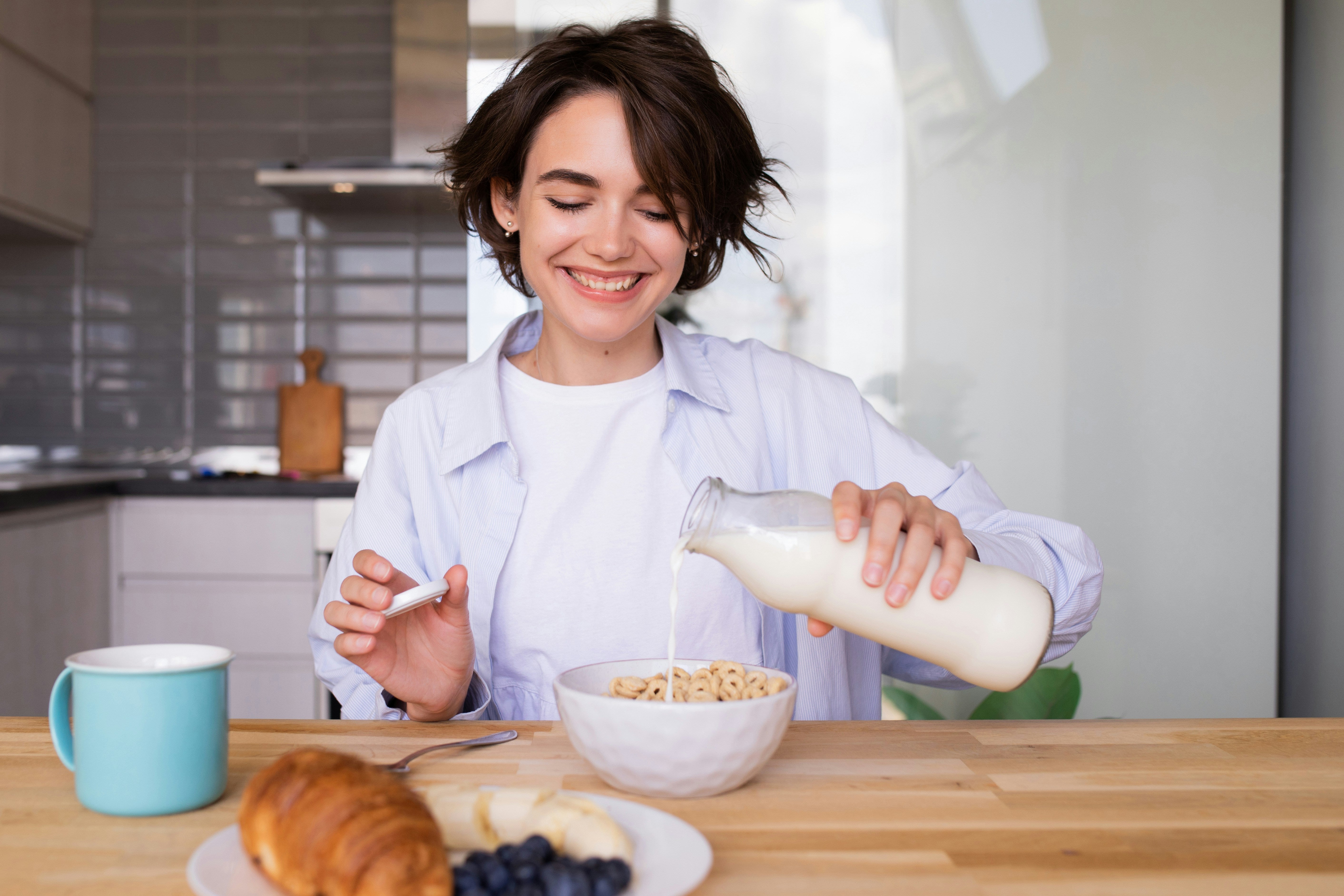 A woman pouring milk into a bowl of cereal, a common breakfast choice that may require lactose-free alternatives for those with intolerance.