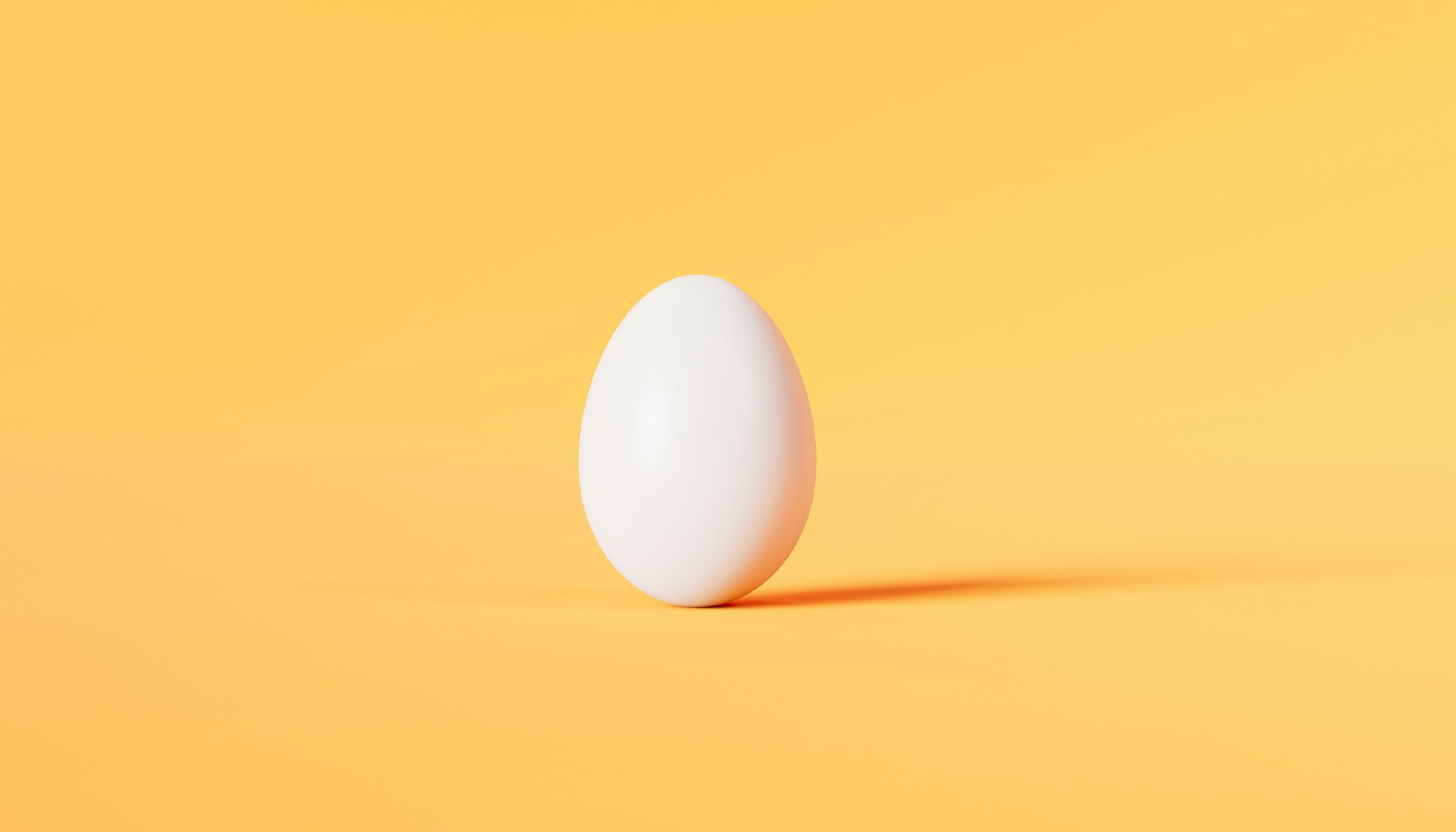 A single white egg on a bright yellow background, highlighting the simplicity of this common dietary staple that can trigger intolerance symptoms for some individuals.