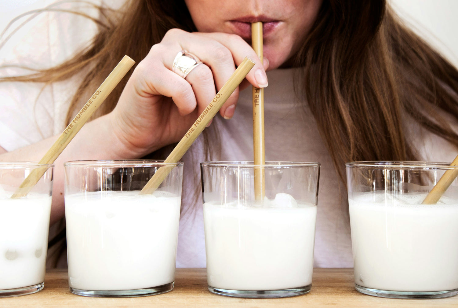 A woman testing different types of milk with wooden straws, emphasising the importance of identifying personal reactions to lactose and milk alternatives.
